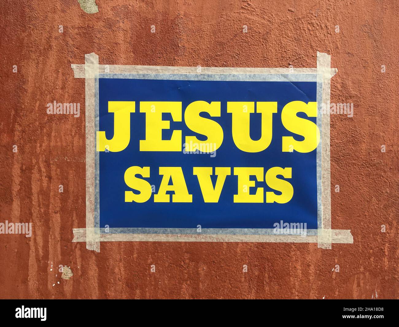 Stockholm, Sweden - September 4, 2020: A small poster taped on a wall with the christian message 'jesus saves' with blue background and yellow text sa Stock Photo