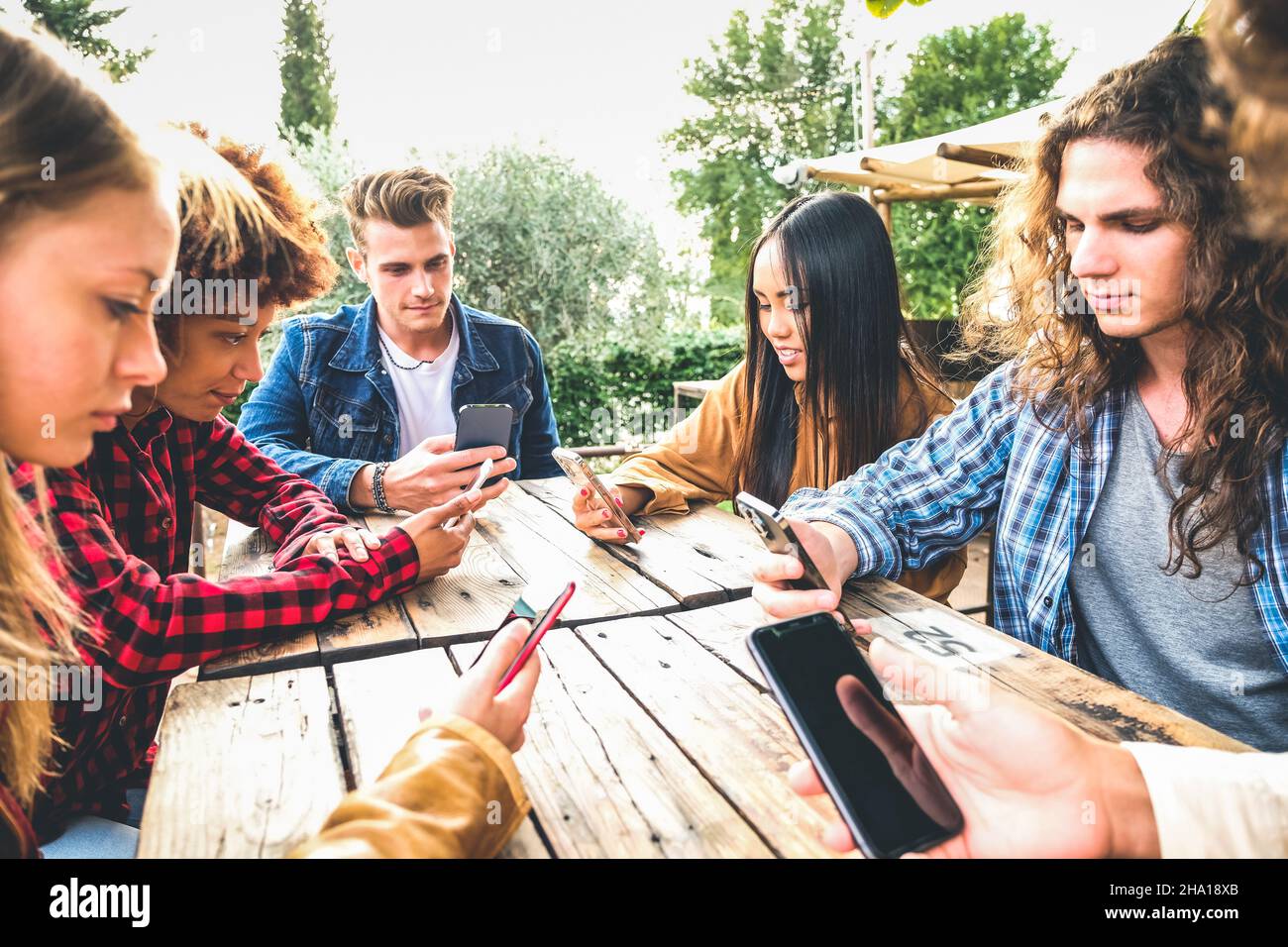 Group of friends checking social media on smartphones at restaurant or pub and ignoring each other Stock Photo