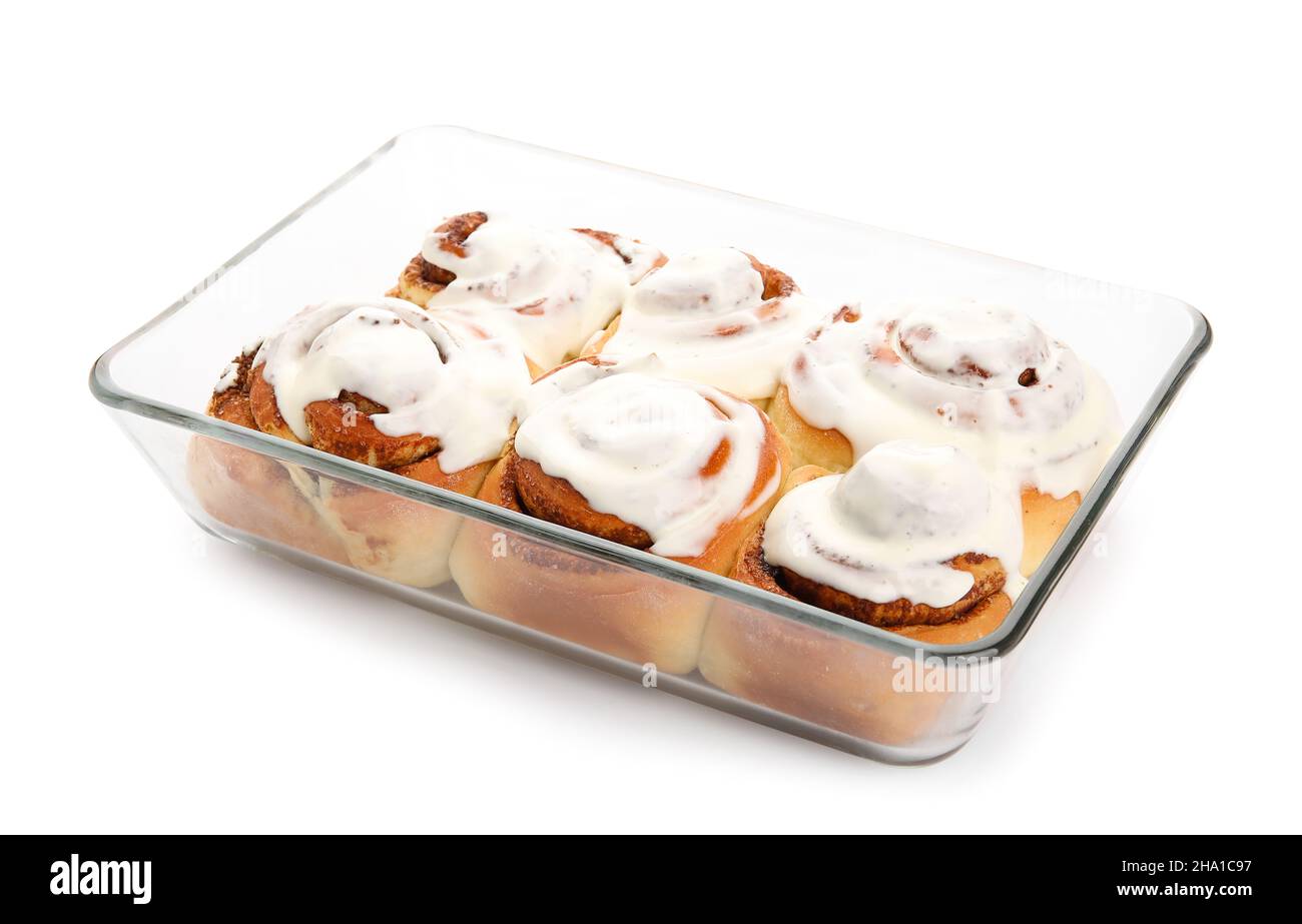 Baking dish of tasty cinnamon rolls with cream on white background ...
