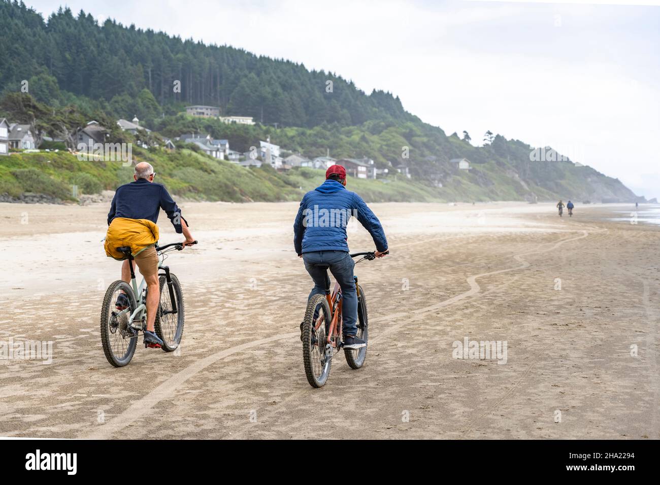 Two amateur men an elderly father and young son travel side by side on the mountain bicycles along the Northwest Pacific Ocean preferring an active he Stock Photo