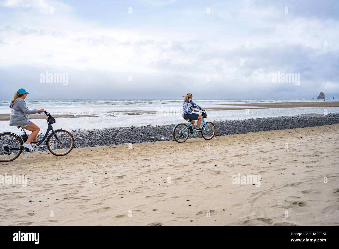 Two middle-aged women amateur cyclists rides bicycles traveling on the cost line along the Northwest Pacific Ocean preferring an active healthy lifest Stock Photo