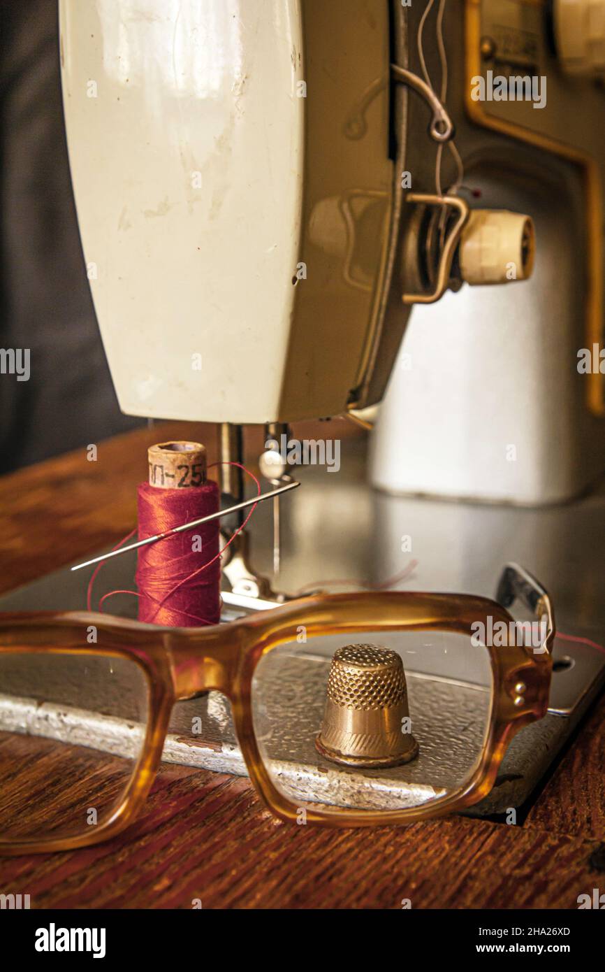 view of the thimble through glasses on the sewing machine table Stock Photo