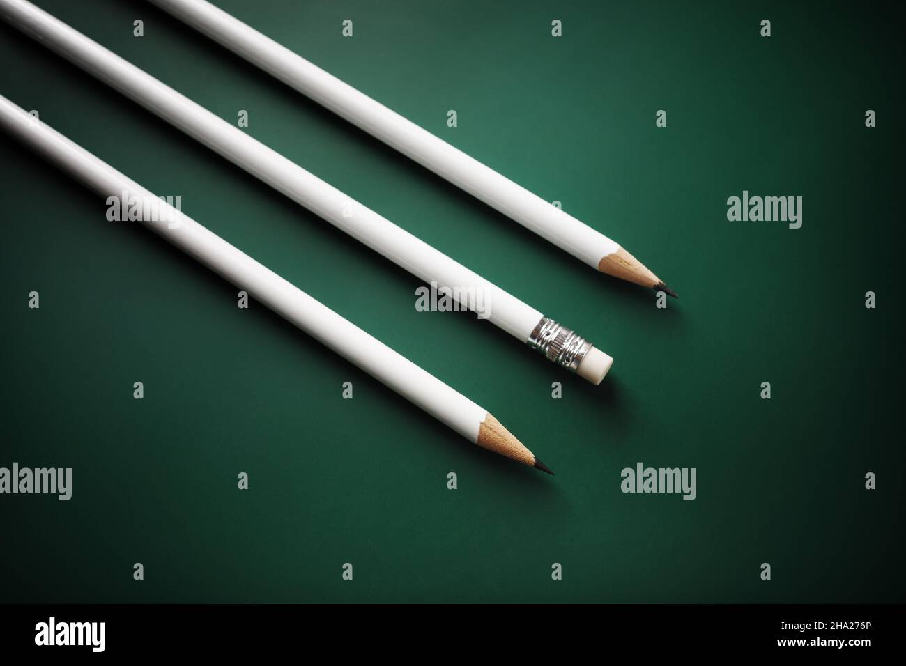 Three blank white pencils on green background. Stock Photo