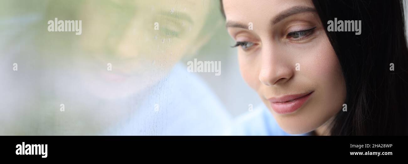 Pensive pensive girl sits alone and looks out window closeup Stock Photo