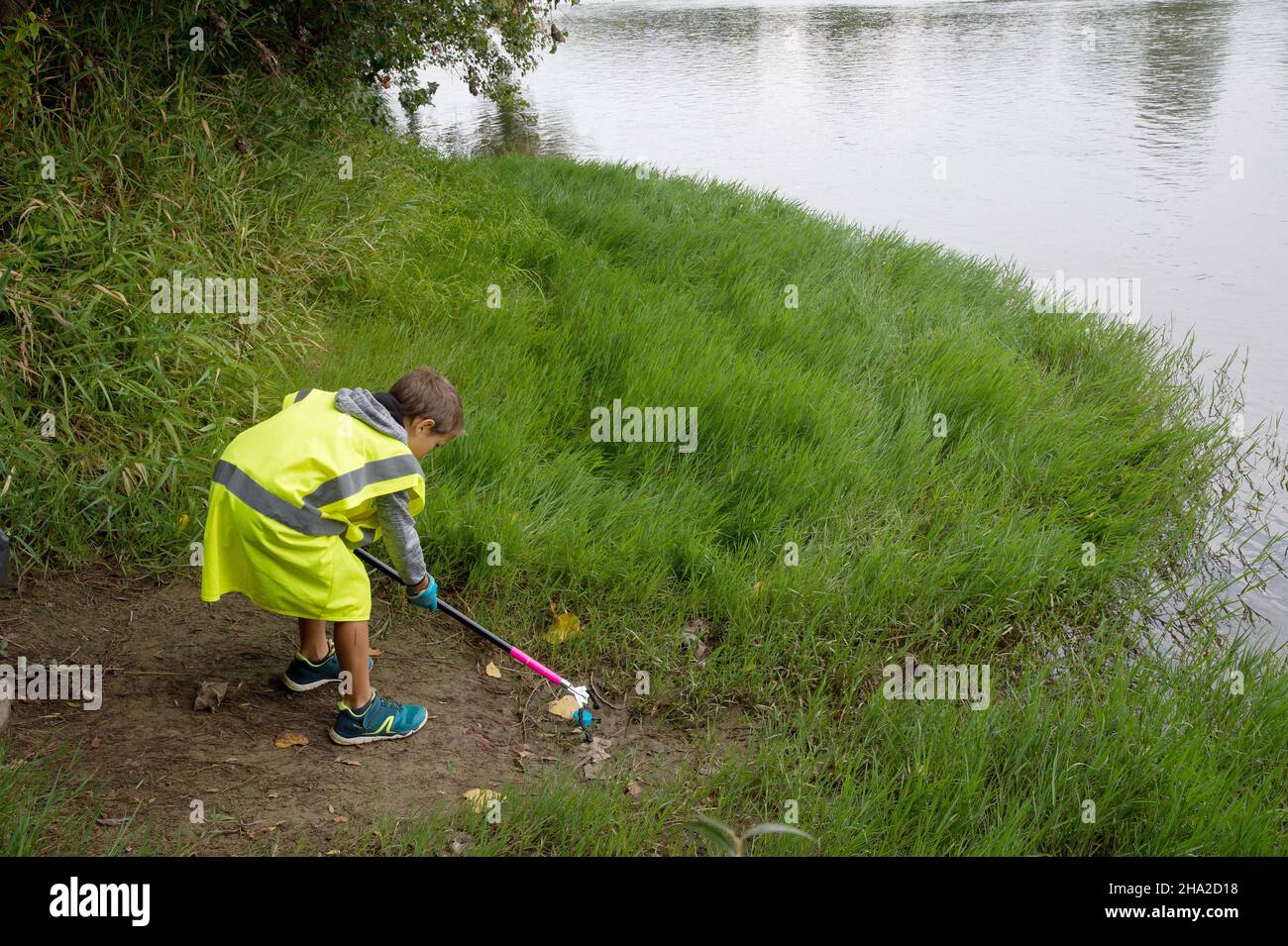 Clean-up operation by the Garonne River in Blagnac, on September 18, 2021. Child, litter-picker a wearing fluorescent yellow vest picking up litter th Stock Photo
