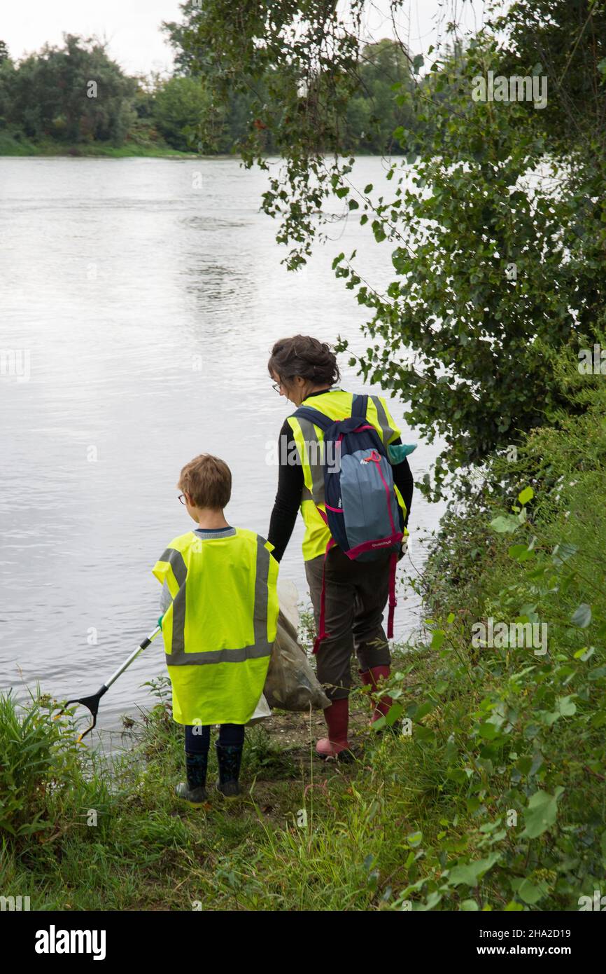 Clean-up operation by the Garonne River in Blagnac, on September 18, 2021. Mother and her son, woman and child wearing fluorescent yellow vests pickin Stock Photo