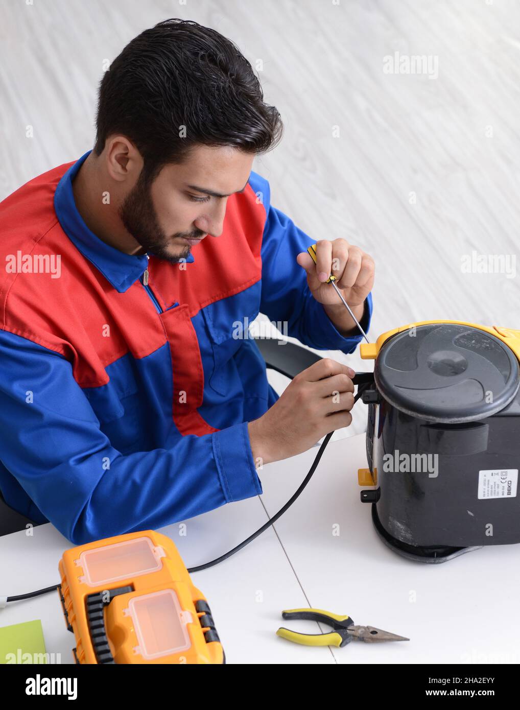 The man repairman repairing vacuum cleaner at service center Stock