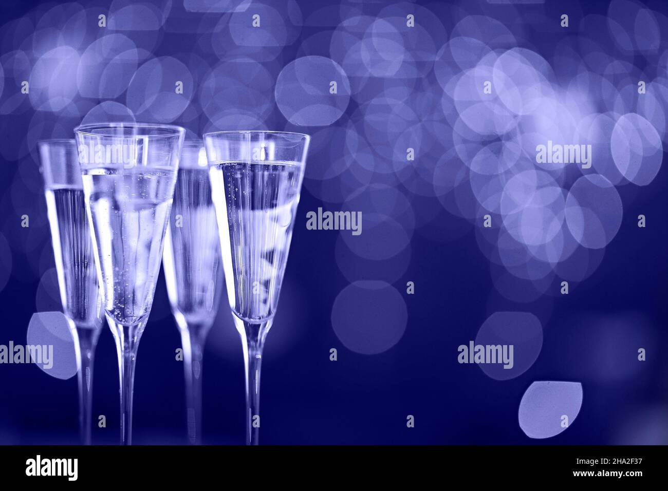 Champagne glasses on lights background. Celebration background. Color of 2022 year, very peri, violet Stock Photo