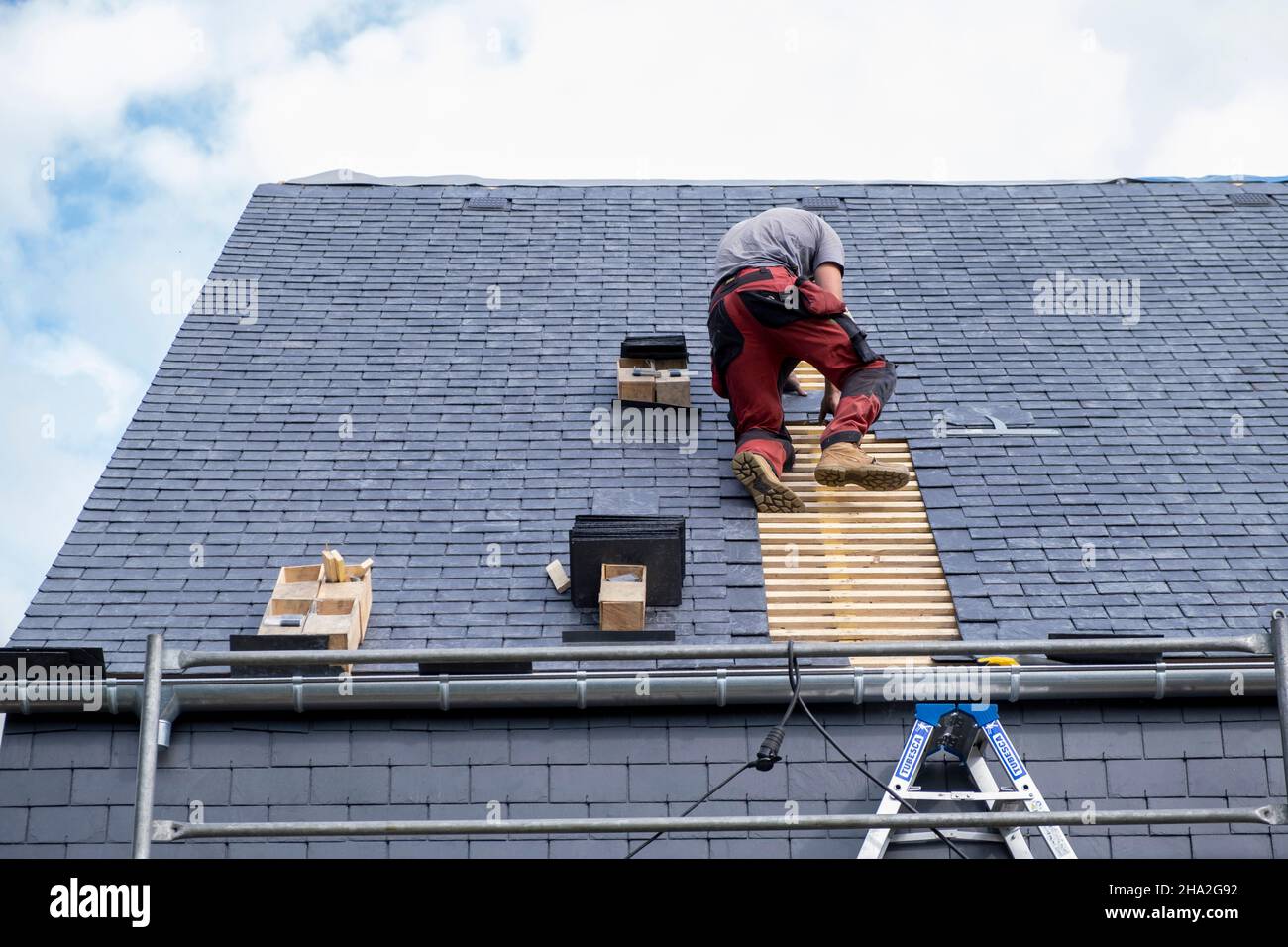 Renovation works, external roof insulation. Roofer specialized in external insulation laying slates on the roof of a house Stock Photo