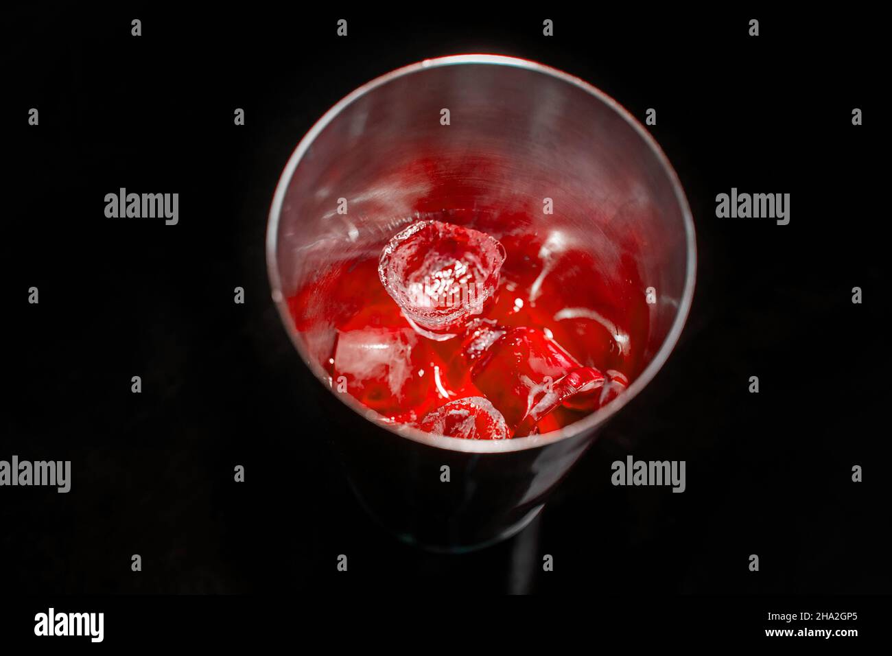 Red cold syrup with ice in a tool for mixing and making alcoholic