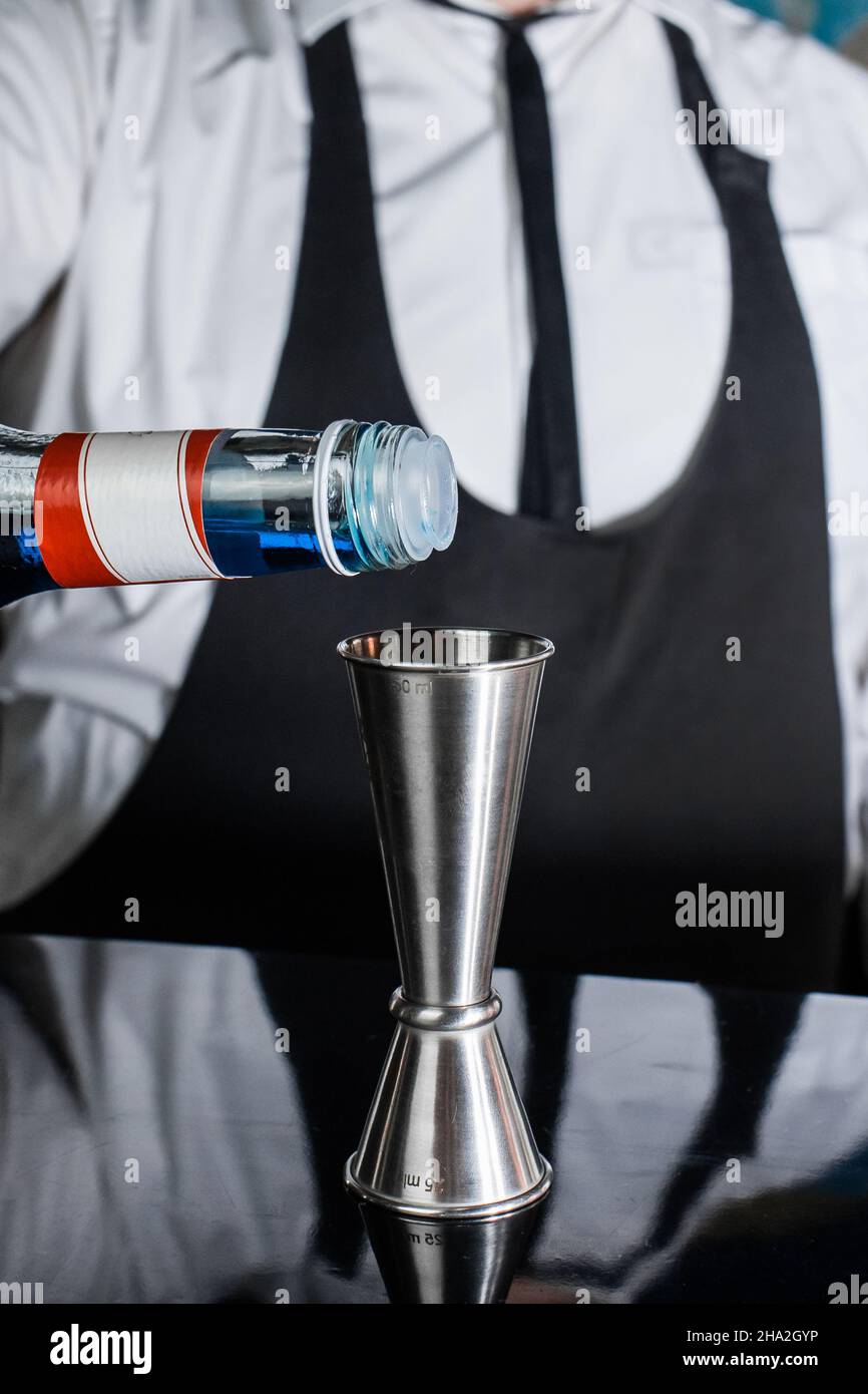 https://c8.alamy.com/comp/2HA2GYP/the-hand-of-a-professional-bartender-pours-blue-syrup-into-a-tool-to-control-the-ingredients-added-to-a-jigger-cocktail-or-measuring-cup-the-process-2HA2GYP.jpg