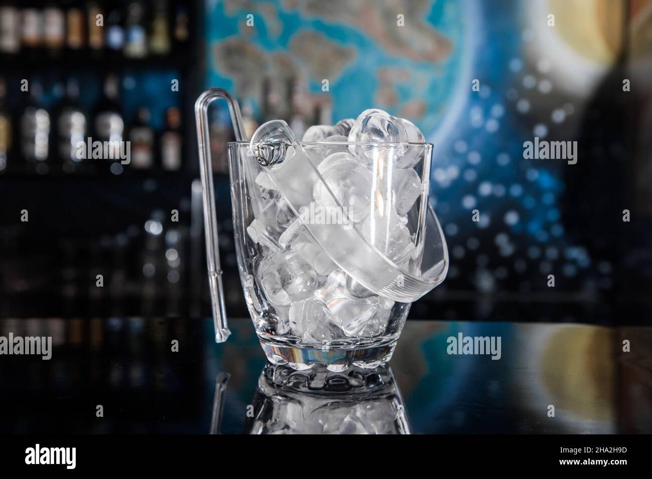 Chilled ice cookware with ice cubes and plastic tongs on the bar ...