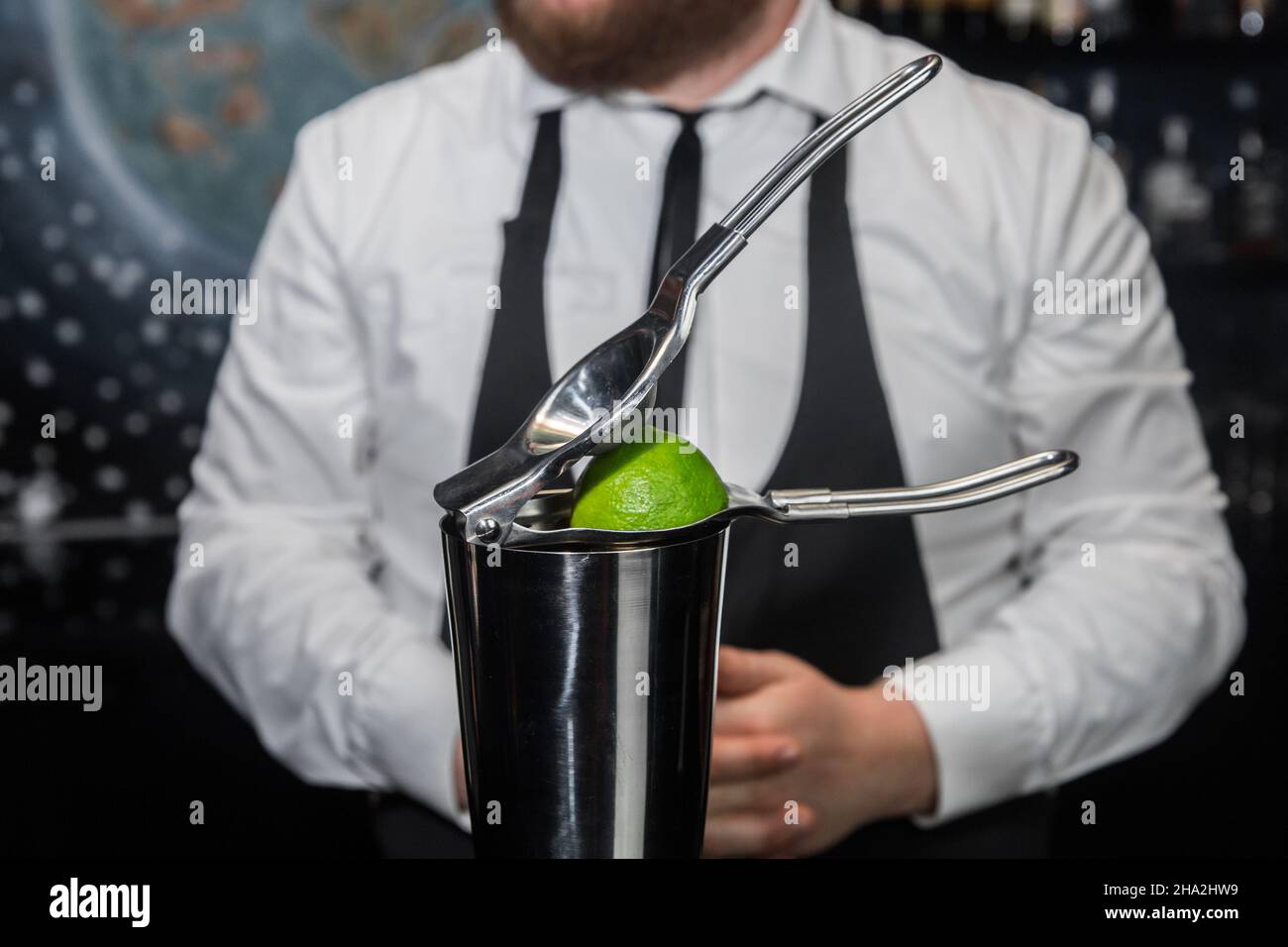 Professional bartender squeeze lime juice with an iron tool with a
