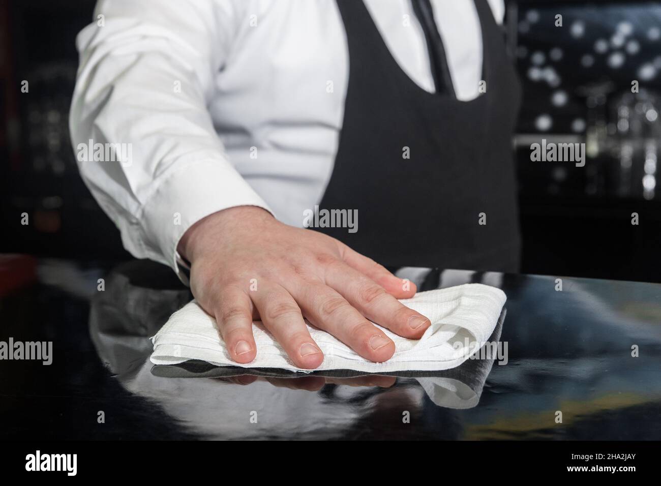 The hand of a professional bartender wipes the bar counter with a