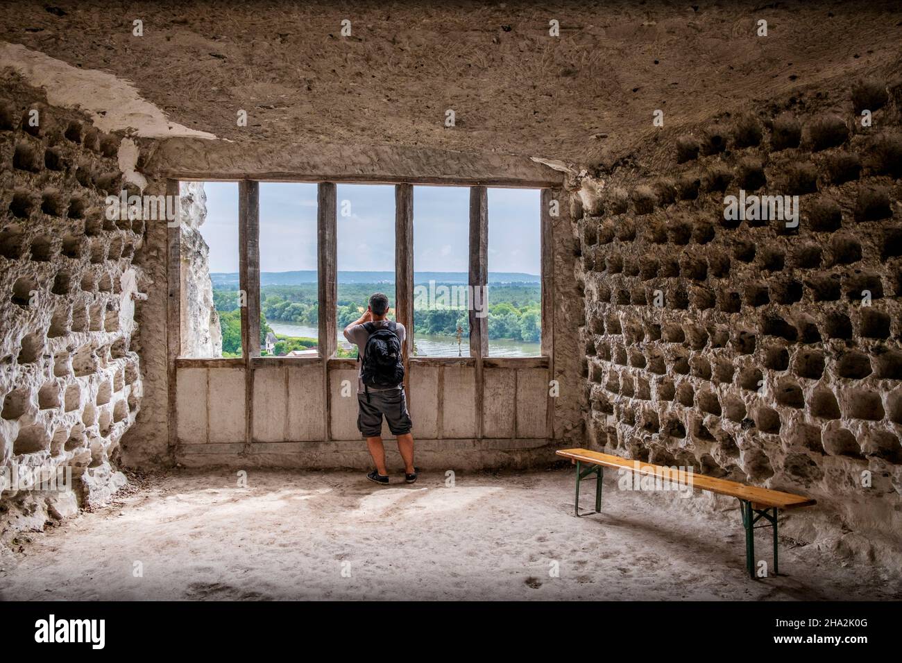 La Roche-Guyon (northern France): troglodyte dovecot of the castle dug in a limestone cliff. Man viewed from behind talking a picture of the landscape Stock Photo