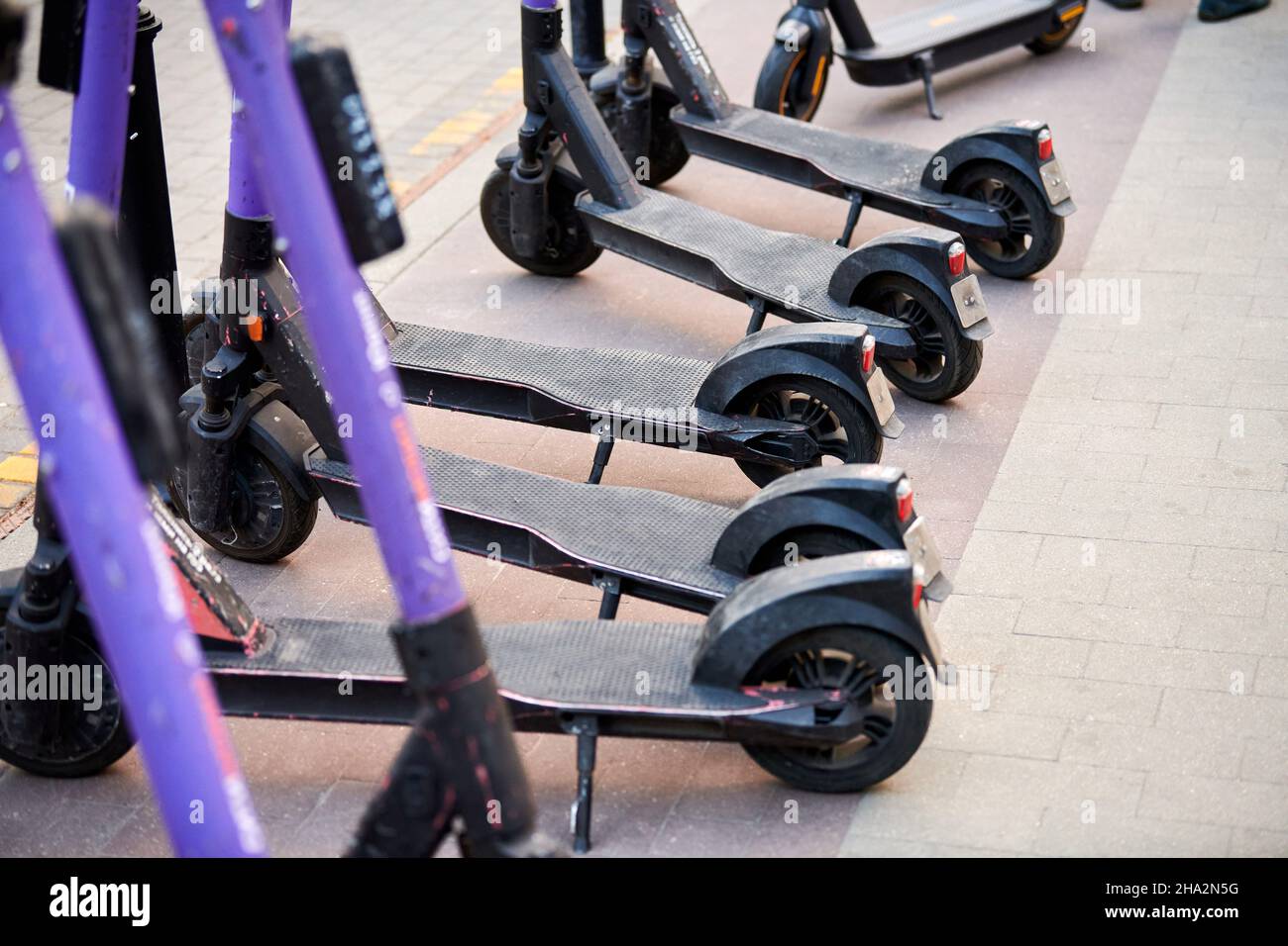 Motorized scooter parking for hourly rent on sidewalk street. Ride