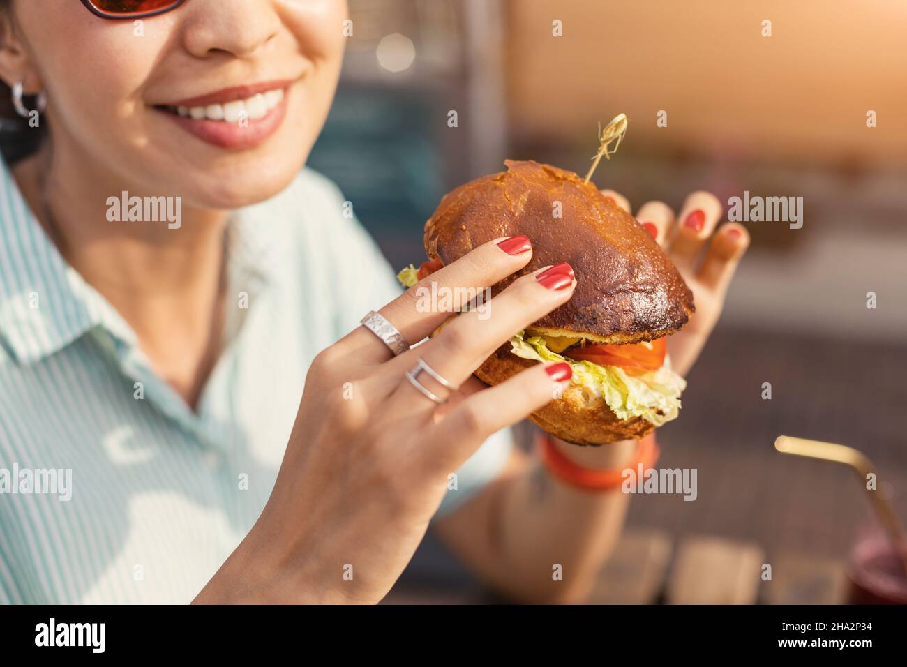 Happy asian young woman eating delicious fastfood burger in street food restaurant Stock Photo