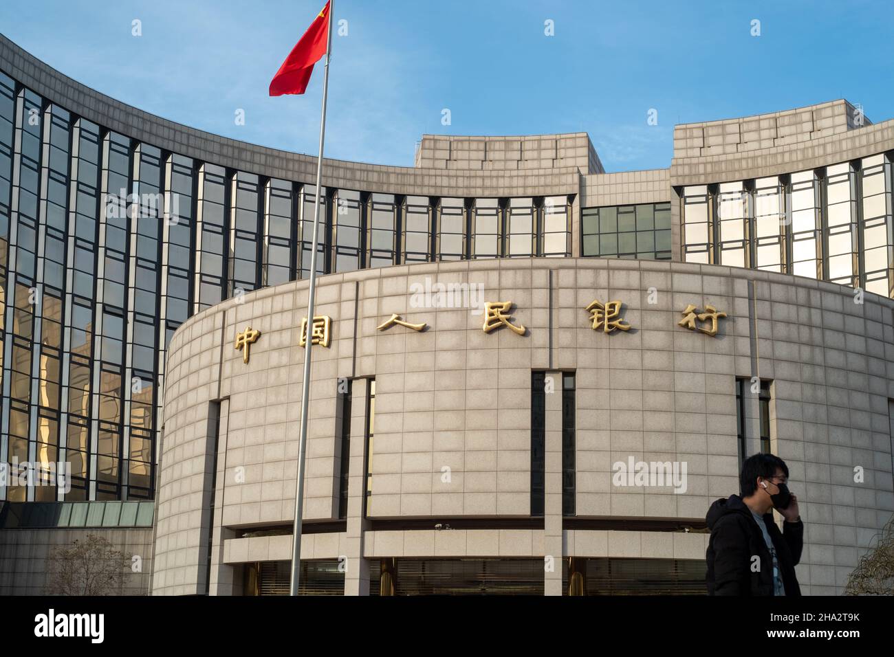 A man uses a mobile phone in front of the headquarters of the People's Bank of China (PBOC), China's central bank, in Beijing. 10-Dec-2021 Stock Photo