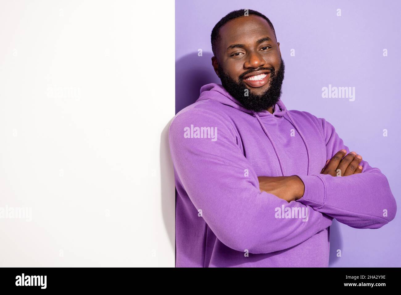 Portrait of attractive cheerful guy demonstrating copy space health care information folded arms isolated on violet purple color background Stock Photo