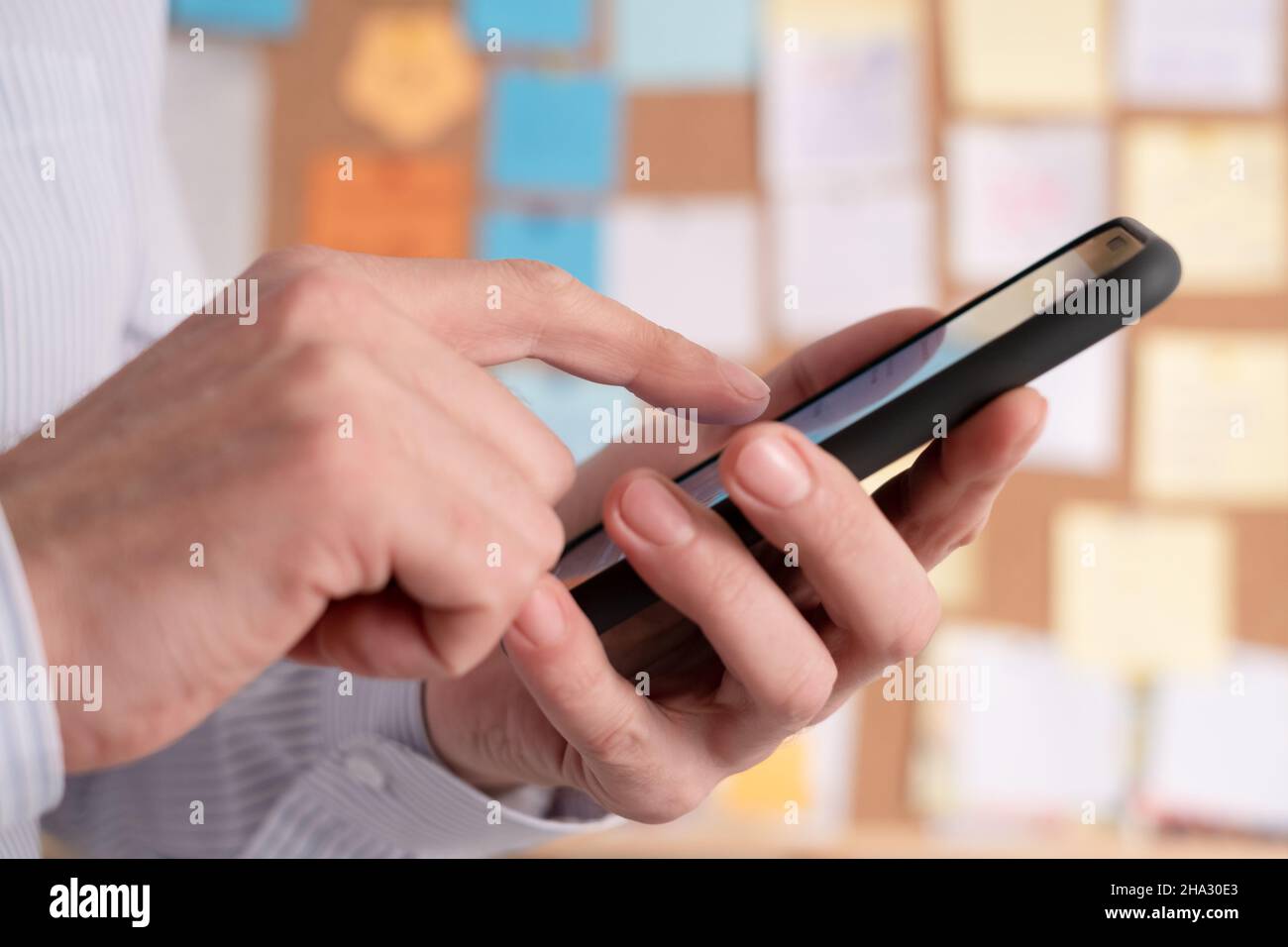 Using a smartphone for planning tasks and calendar events in the office, use of digital technologies to change a business model. Sticky notes on a cor Stock Photo