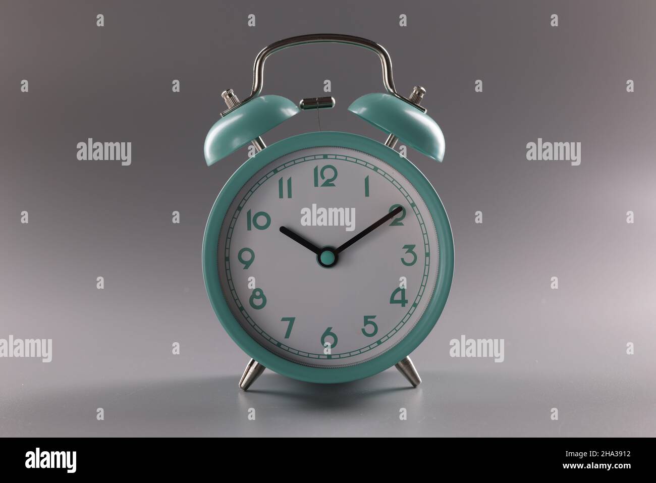 Turquoise alarm clock at ten o'clock on gray background. Time control