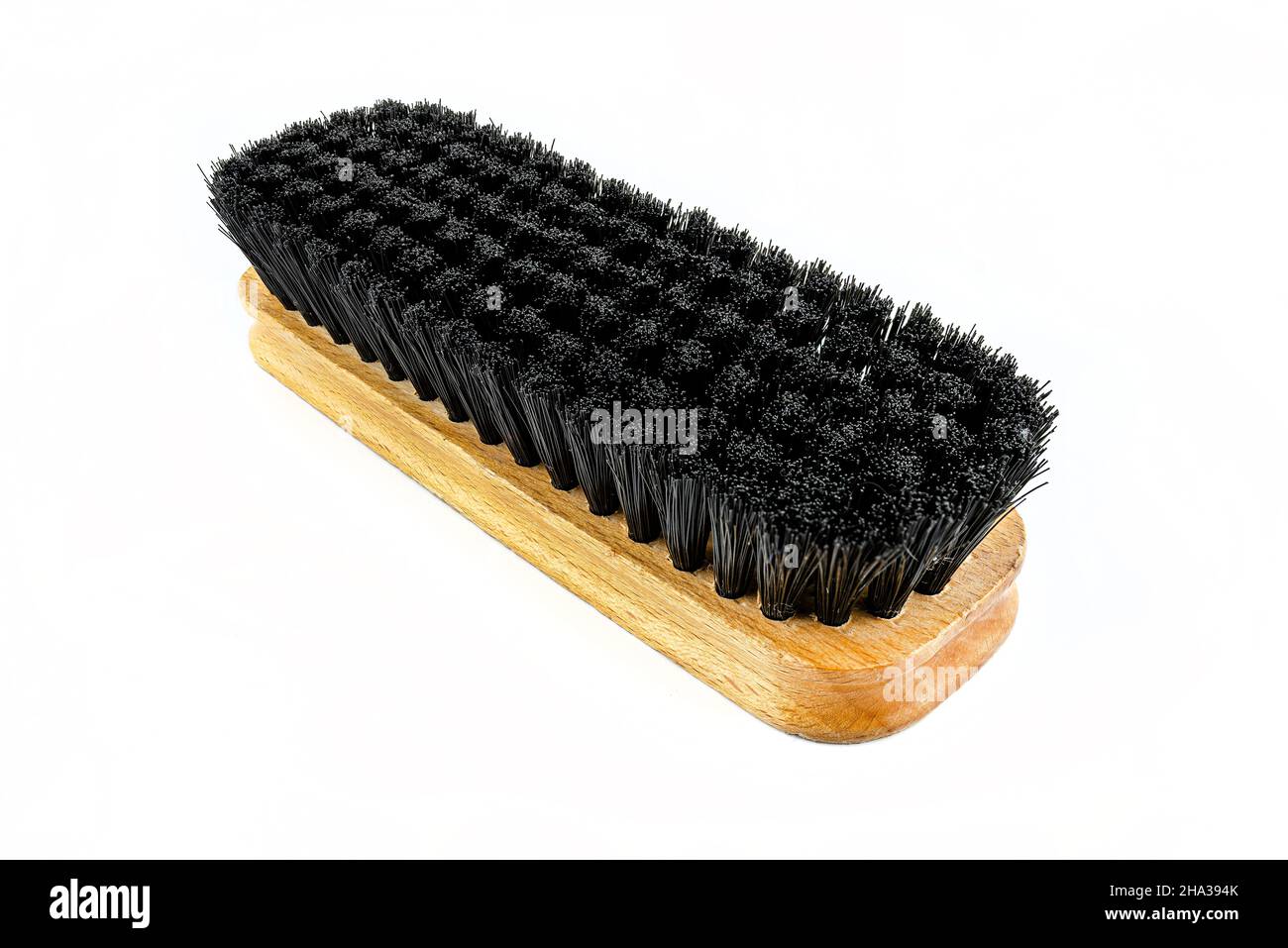 Macro photo of a wooden black bristle shoe brush, isolated on a white background. Stock Photo