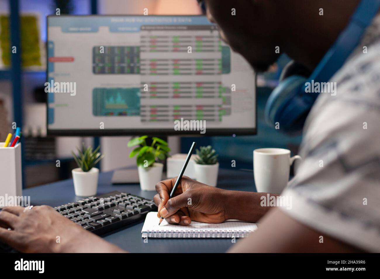 African american business trader writing crypto investment value on  notebook while analyzing stock market investment on computer. Broker man  checking marketing trading charts working remote from home Stock Photo -  Alamy