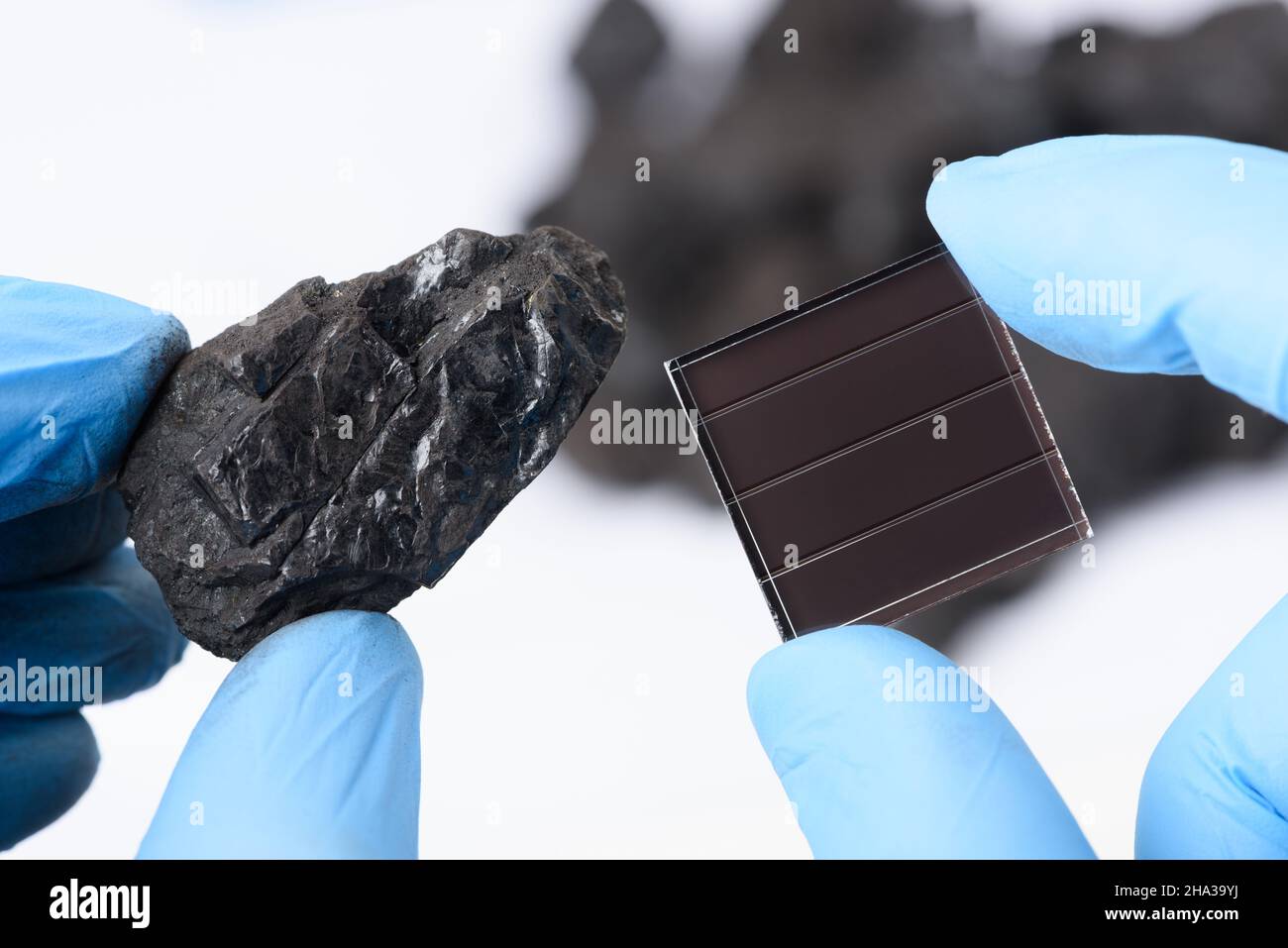 Coal next to solar panel in scientist hands in laboratory. Fossil fuel