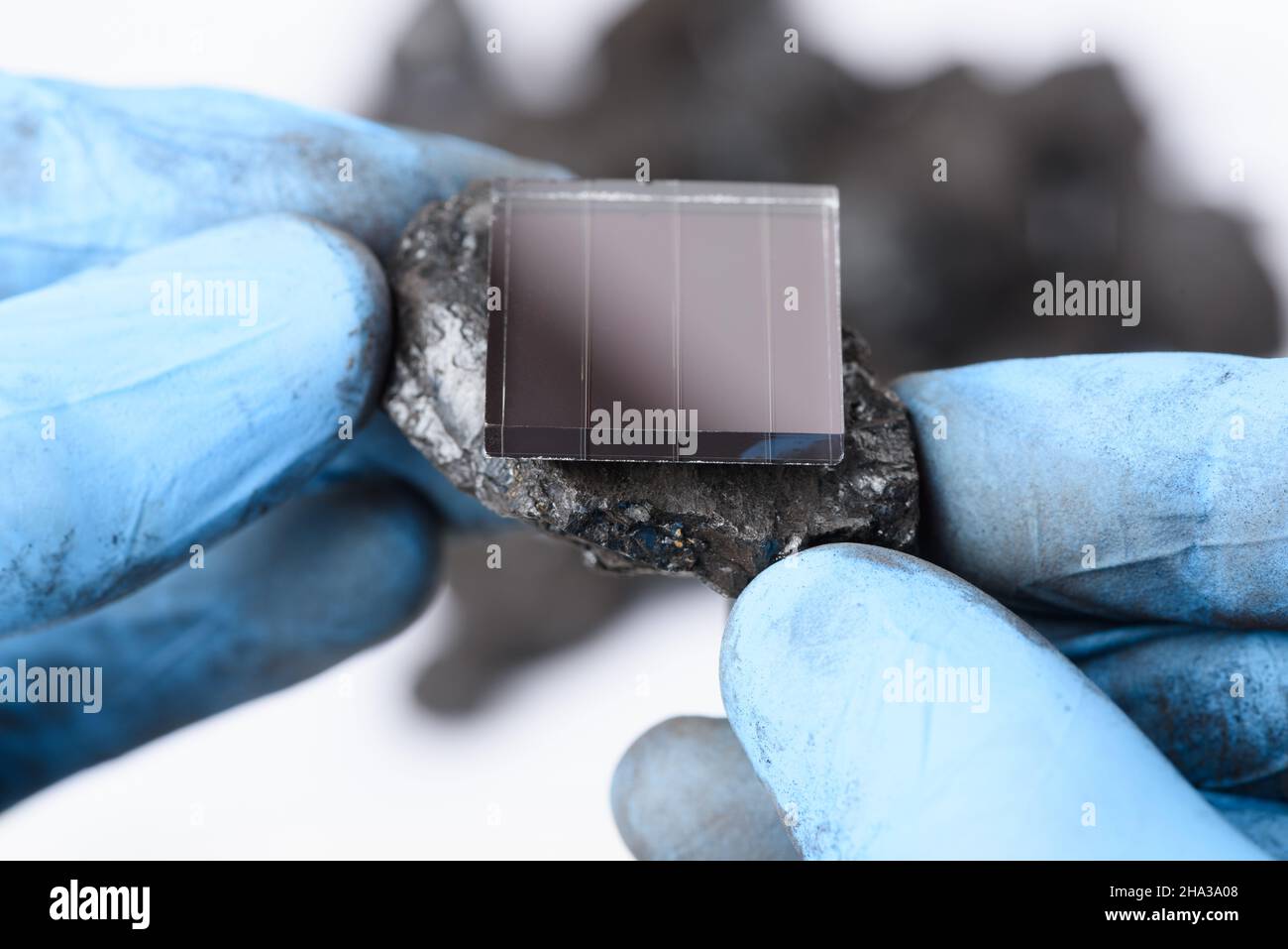 Solar panel on lump of coal in scientist hands. Fossil fuel transition and renewable energy reseach concept. Stock Photo