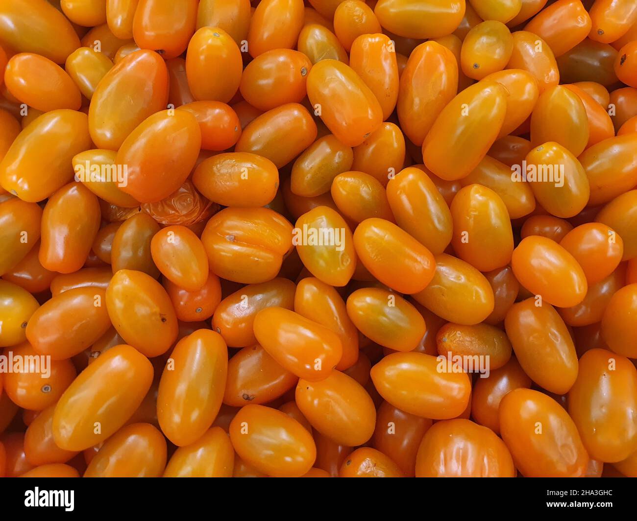 Cherry tomatoes, many, yellow (Solanum lycopersicum var. Cerasiforme, still with the stem, in the market. Top view. Stock Photo