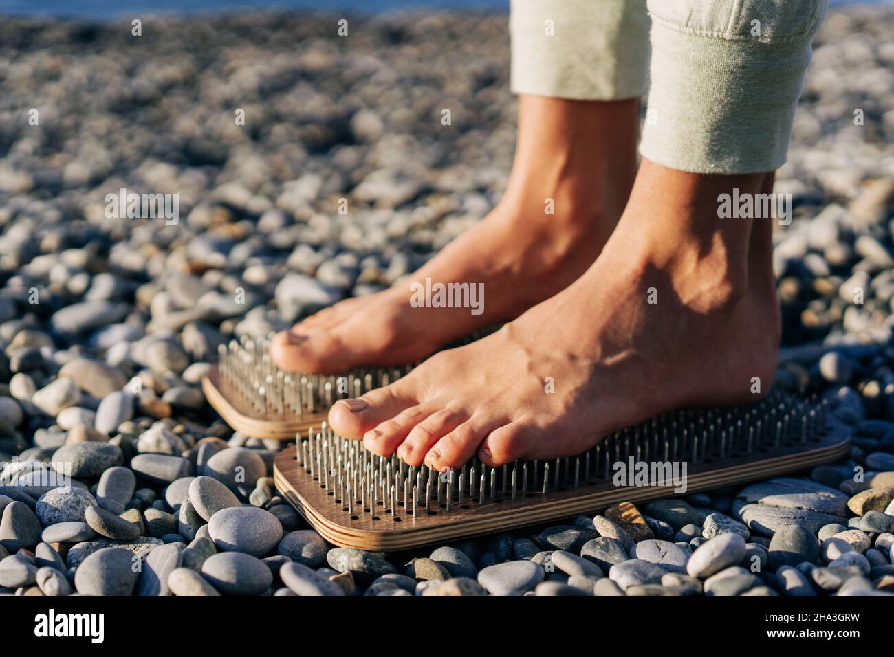 Close up of female feet on boards with nails. Stock Photo