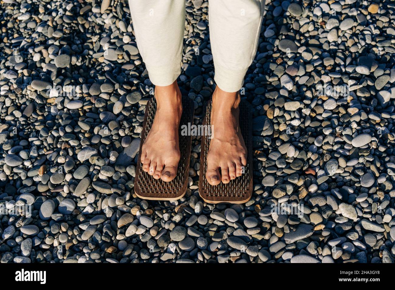 Close-up of female feet on boards with nails practice acupressure. Stock Photo