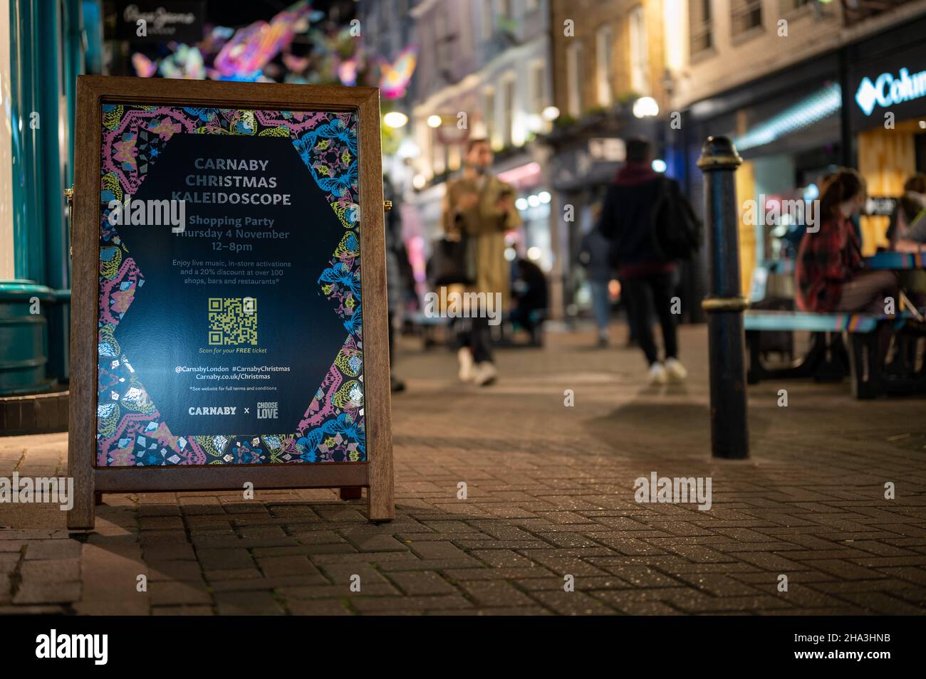 LONDON - NOVEMBER 1, 2021: Carnaby Street Christmas lights advertisement with shoppers out of focus in the background Stock Photo