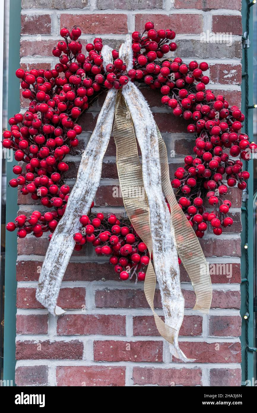 A bright red holly berry holiday Christmas wreath with gold ribbon hung ...
