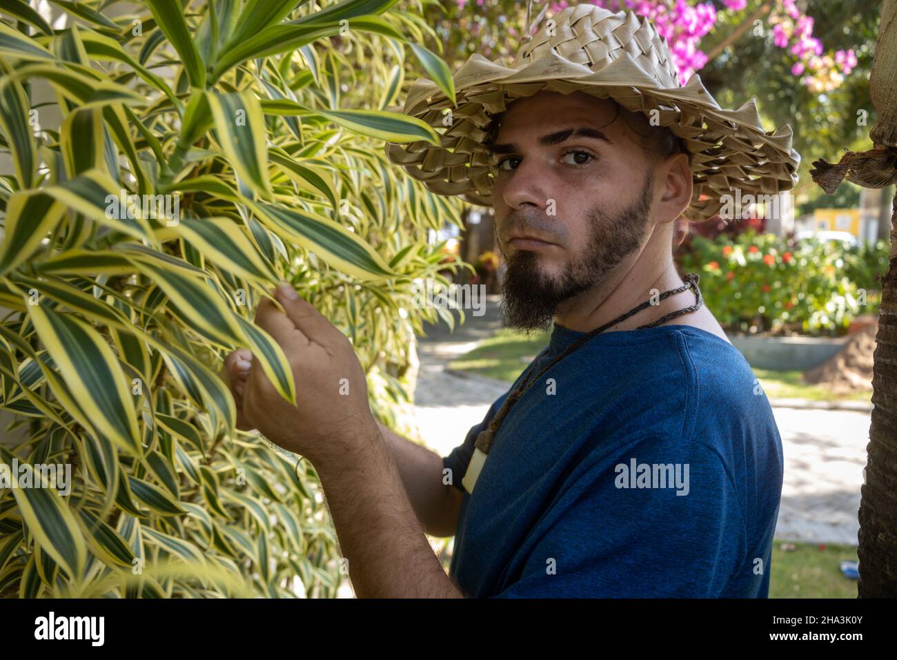 Young adult Caucasian man and hippie gardener appearance with serious look in the park. Stock Photo