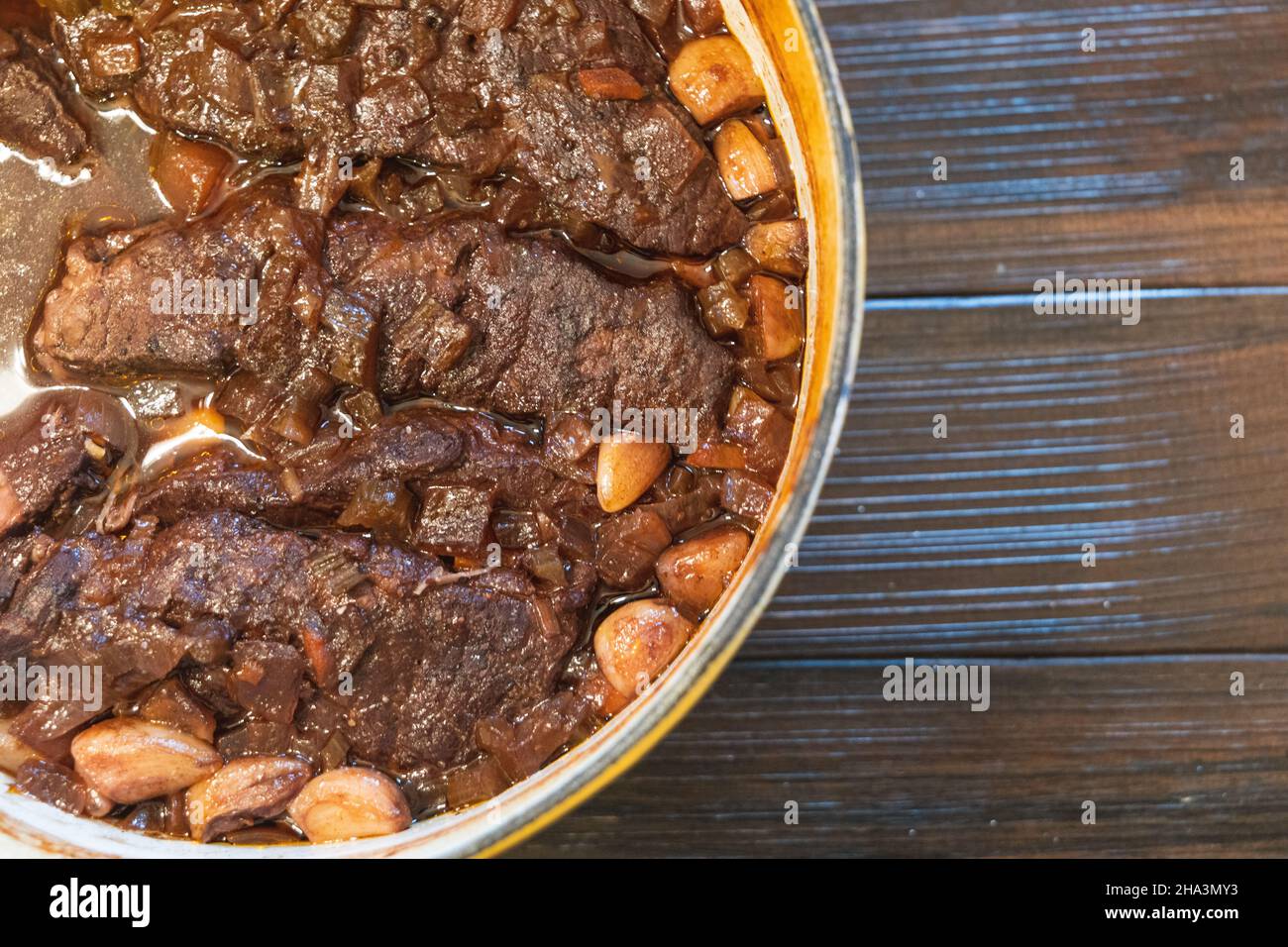 A yellow dutch oven with homemade braised beef short ribs in wine and garlic Stock Photo