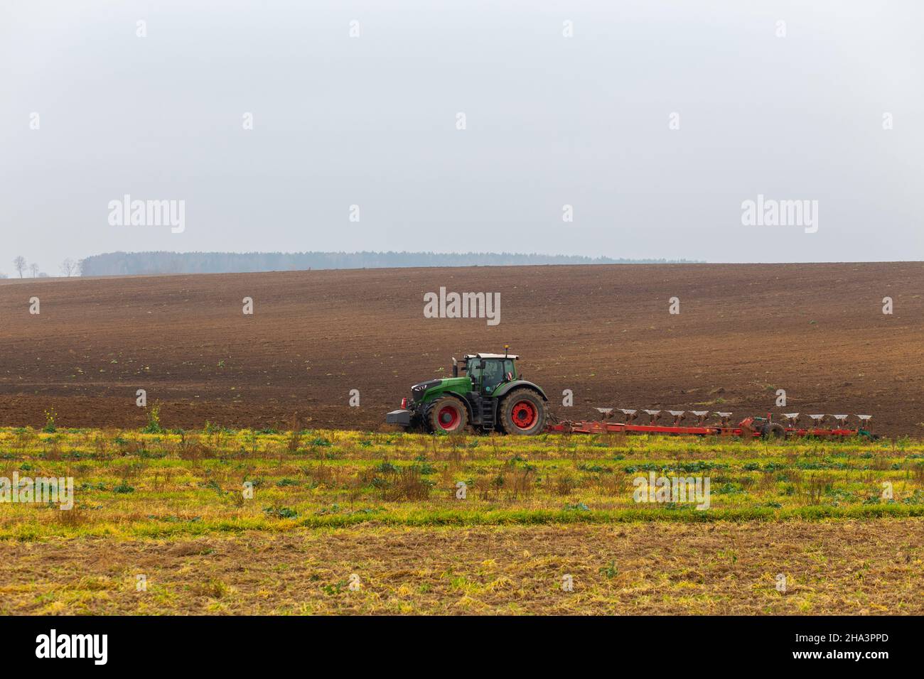 A tractor with a large double plow plows a field in autumn Stock Photo Alamy