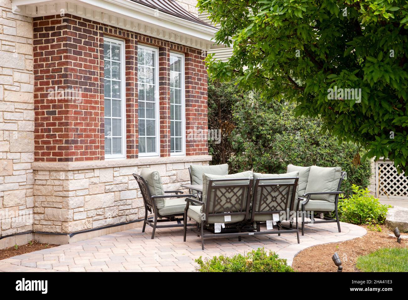 A brick patio of a luxury, stone home with chairs sitting around a ...
