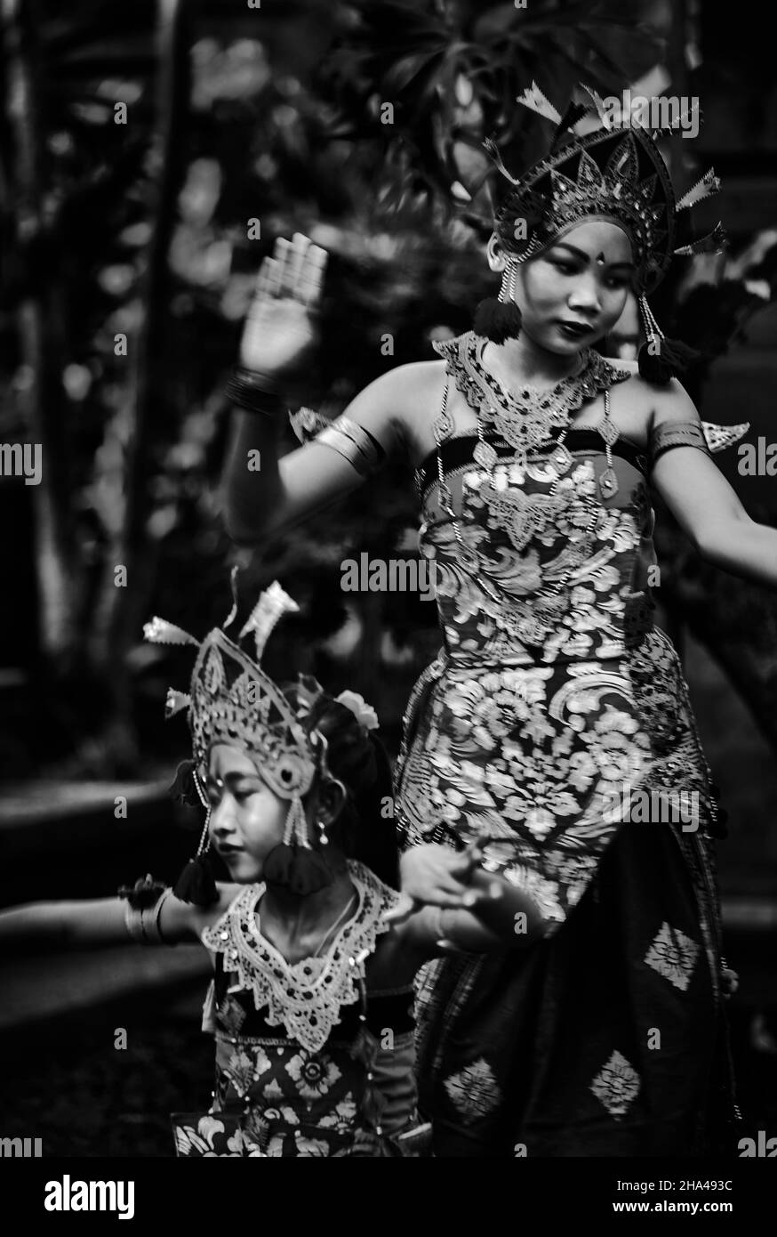 Two young Balinese girls perform a traditional dance in costume at their family compound in Ubud Bali Indonesia. Stock Photo