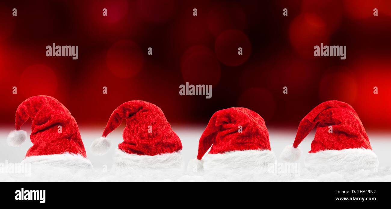 red christmas hats against a blurred red background Stock Photo