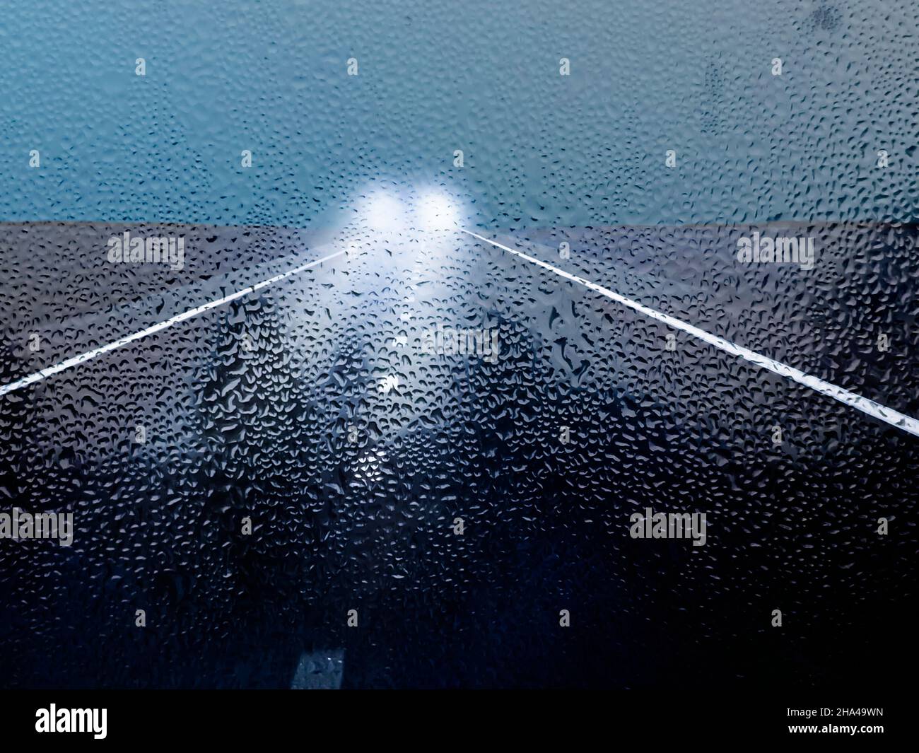 rainy road and oncoming traffic with headlights Stock Photo