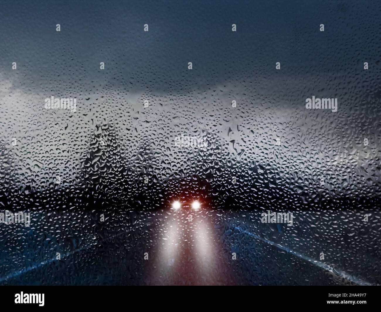 rainy road and oncoming traffic with headlights Stock Photo