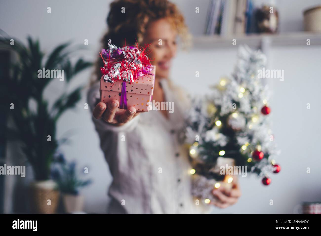 close up of christmas gift and defocused happy woman holding tree and decoration at home during xmas celebration holidays seasons. concept of gift exchange and people Stock Photo