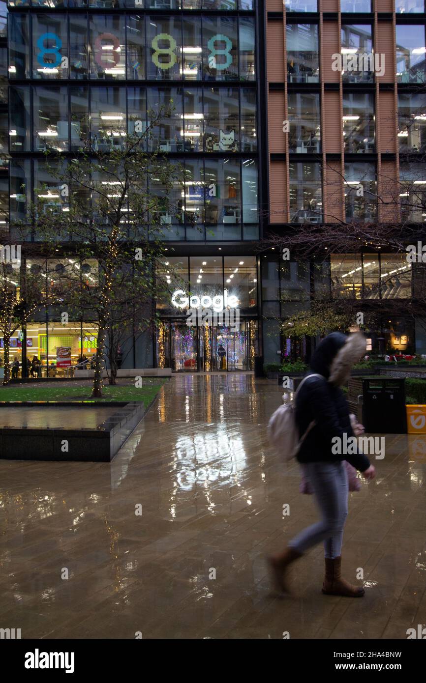 Google offices in Kings Cross London with sign reflected in rain as workers walk past building Stock Photo