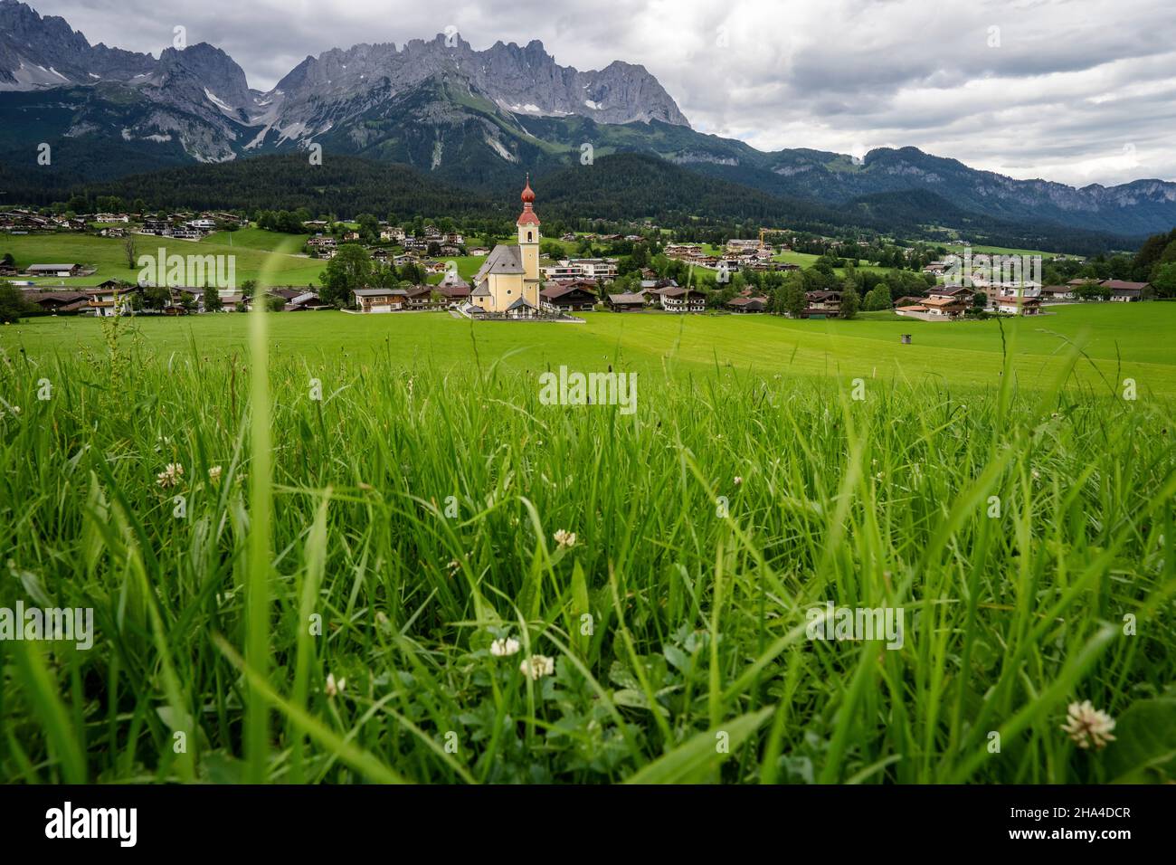 yellow local church in ellmau. village of going. wilden kaiser mountains in background. tirol,alps,austria. Stock Photo