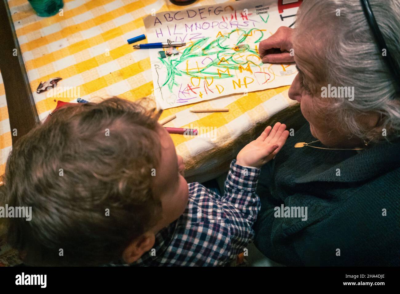 Grandmother and granddaughter play together making drawings. Concept of family and generations. Italy Stock Photo