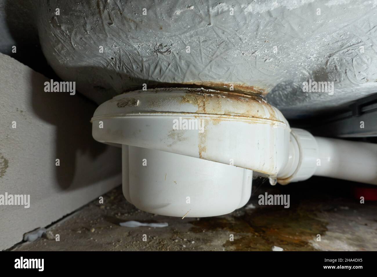 Leaking siphon of a shower tray in the bathroom, causes water damage. The cause is incorrect installation or clogging of the pipe. Building drying and Stock Photo