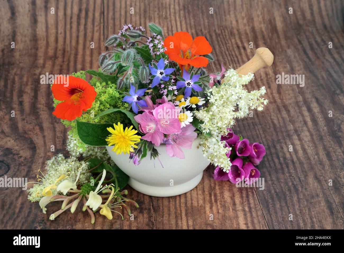 Edible flowers and herbs for natural plant based herbal medicine remedies and food decoration in a mortar. Alternative health and wellness concept. Stock Photo