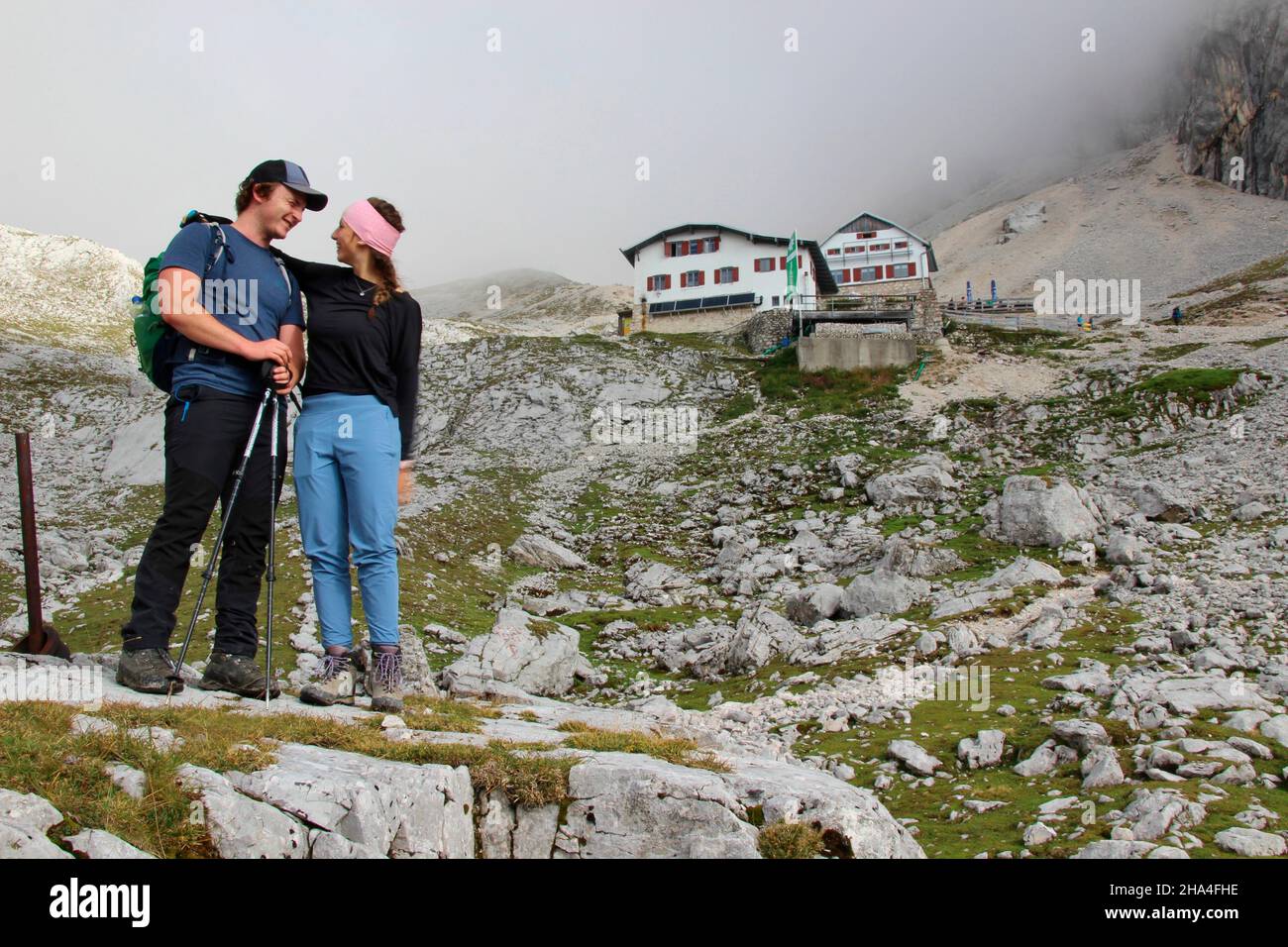 young couple on hike to zugspitze 2962 m,in the background the knorrhütte (2051m) in the early morning fog,wetterstein mountains garmisch-partenkirchen,upper bavaria,bavaria,southern germany,germany,europe, Stock Photo
