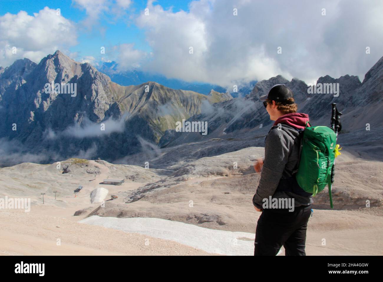 young man hiking on the zugspitze,zugspitzplatt,vl the hochwanner with 2744 m the second highest mountain in germany,wetterstein mountains blue sky,clouds,cloud mood,garmisch-partenkirchen,loisachtal,upper bavaria,bavaria,southern germany,germany,europe, Stock Photo